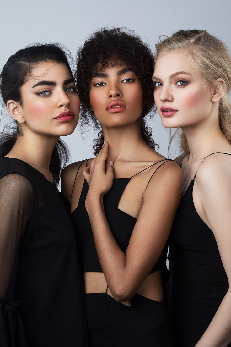 three beautiful young women standing next to each other wearing black clothing and posing for the camera