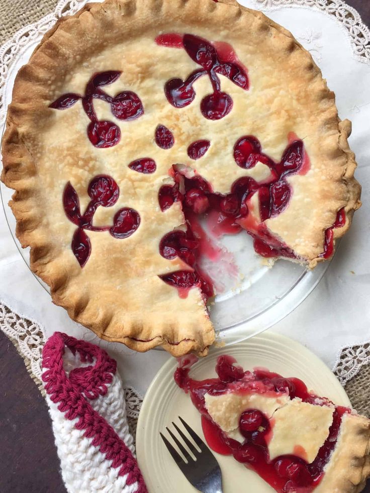 a pie is sitting on a doily with a slice cut out and ready to be eaten