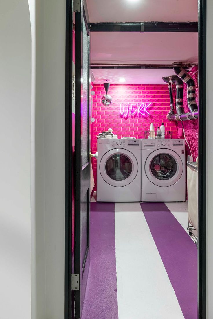 a washer and dryer in a room with pink brick wall behind the door