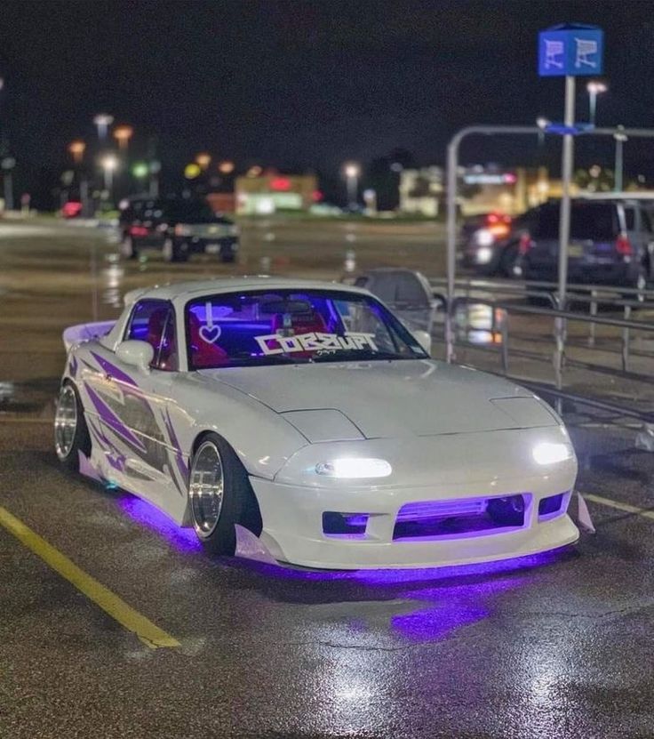 a white car with purple lights parked in a parking lot