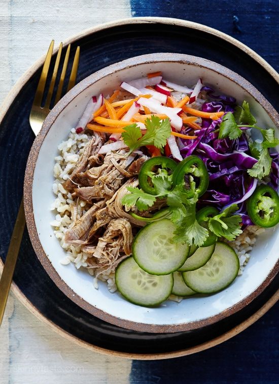 a white bowl filled with meat and veggies on top of a blue place mat