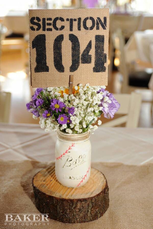 a mason jar filled with purple and white flowers sitting on top of a wooden slice