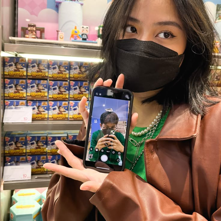 a woman wearing a face mask holding up her cell phone