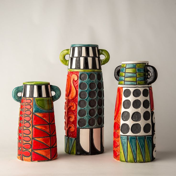 three colorful ceramic vases sitting next to each other