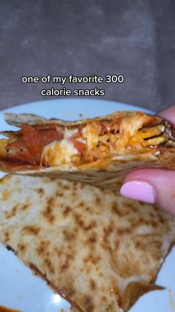 someone is holding a slice of pizza on a plate with the words, one of my favorite 300 calorie snacks