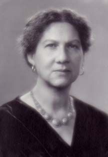 an old black and white photo of a woman in a dress with pearls on her necklace