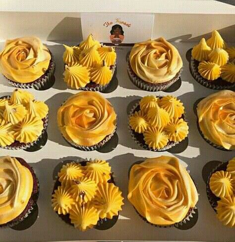 twelve cupcakes with yellow frosting in a box