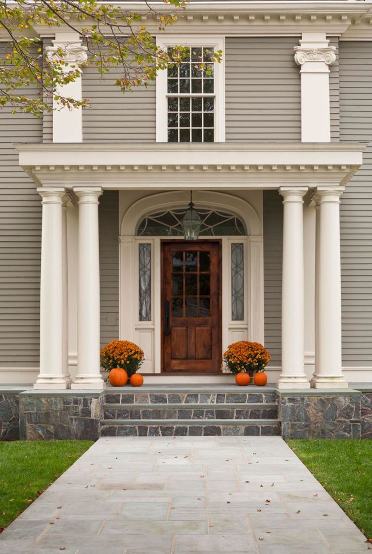 an elegant house with columns and two pumpkins on the steps