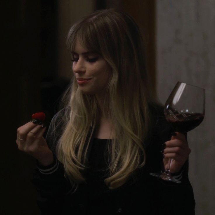 a woman holding a glass of wine in her hand