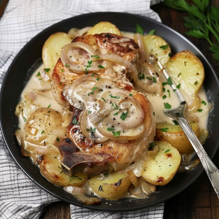 a plate filled with chicken and potatoes covered in gravy on top of a wooden table