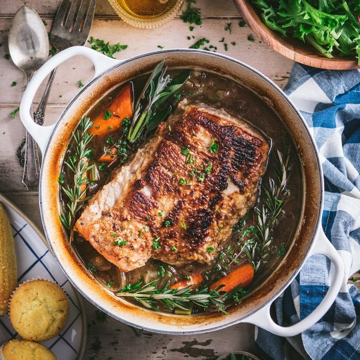 a pot filled with meat and vegetables on top of a table next to some bread