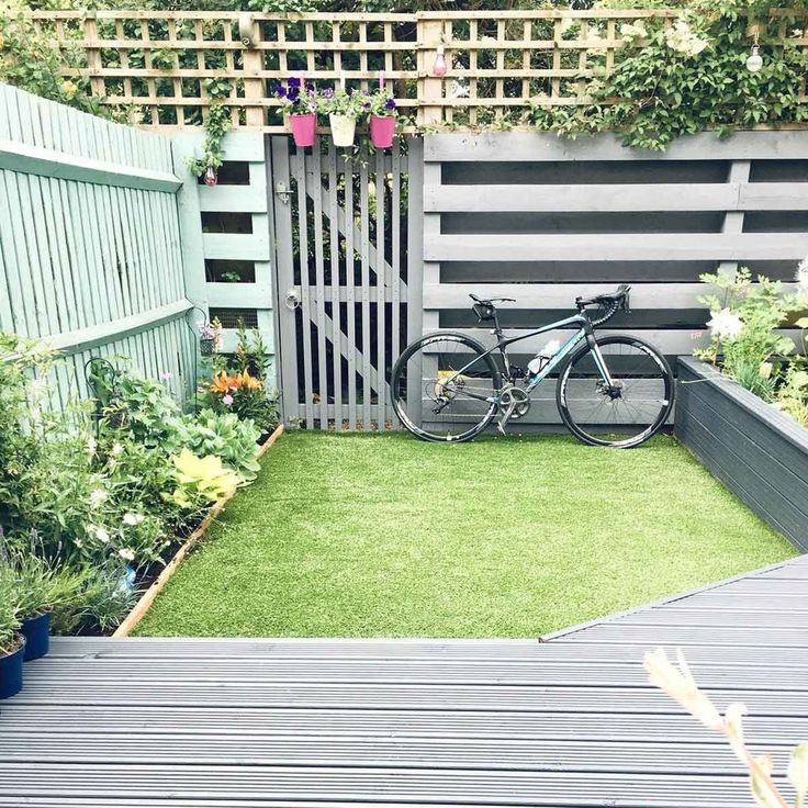 a bicycle is parked on the grass in front of a wooden fence and flower garden