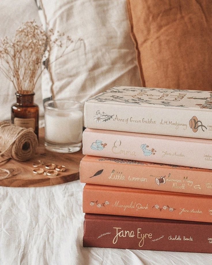 a stack of books sitting on top of a bed next to a glass of milk