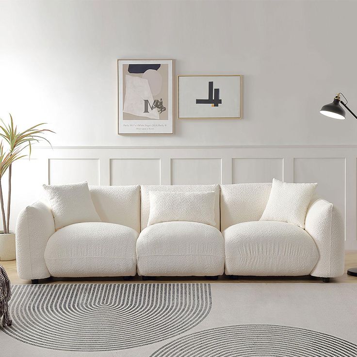 a white couch sitting in a living room on top of a rug next to a lamp