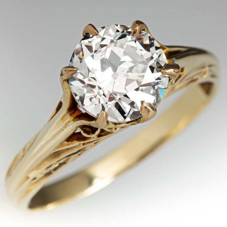 an old - fashioned engagement ring with a round diamond in the center and two tone gold band