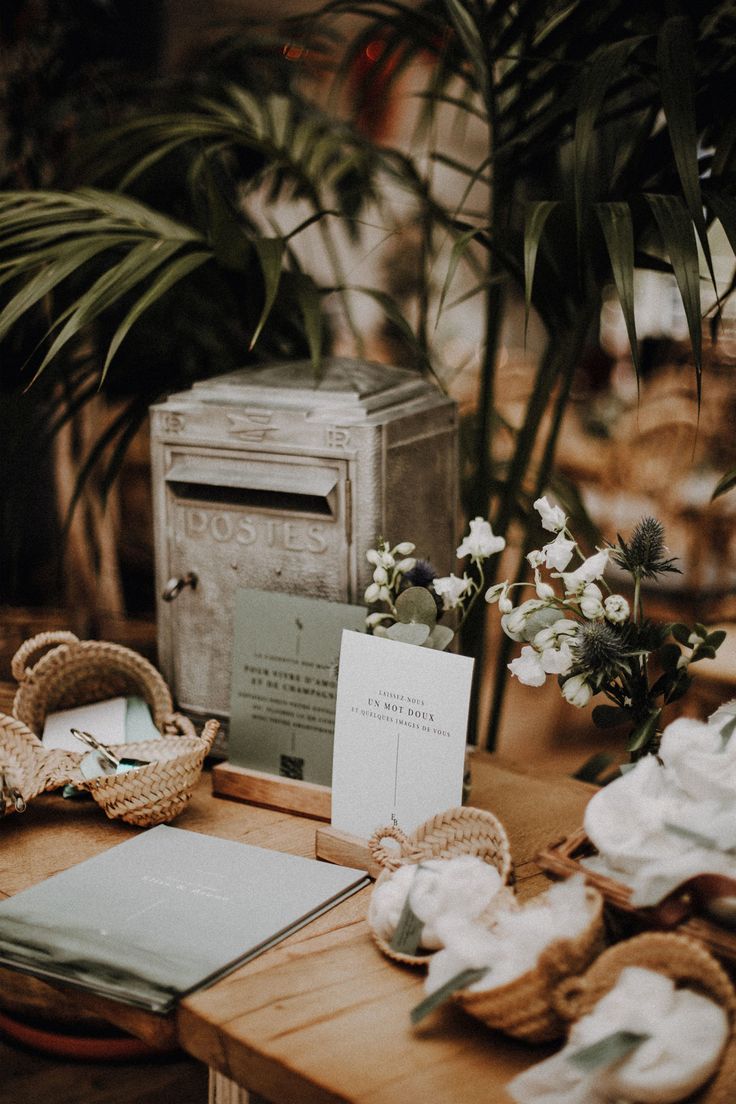 a wooden table topped with lots of plates and napkins next to potted plants