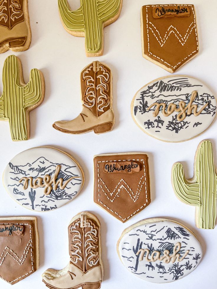 decorated cookies are arranged in the shape of cactus, boots and western style letters on a white surface