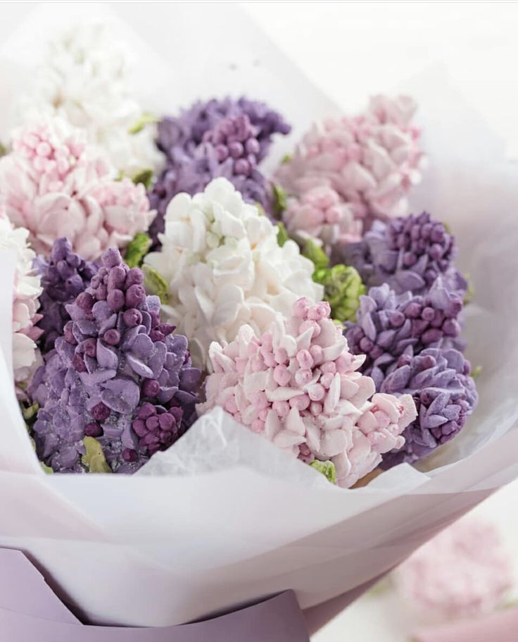 a bunch of flowers that are in some kind of paper bag on a table with pink and purple colors