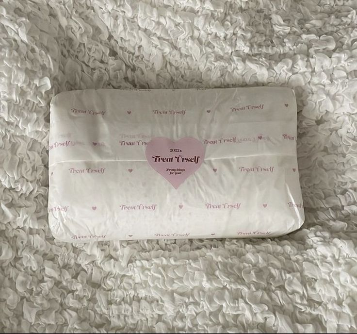 a pink heart shaped pillow laying on top of a bed