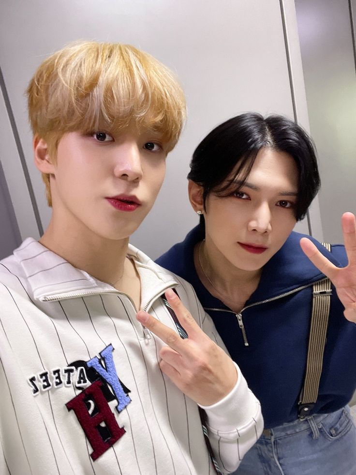 two young men standing next to each other in front of a mirror and making the peace sign