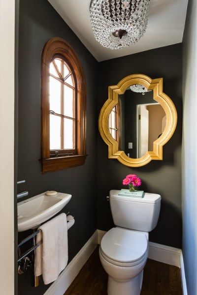 a white toilet sitting in a bathroom next to a sink under a mirror and a gold framed mirror