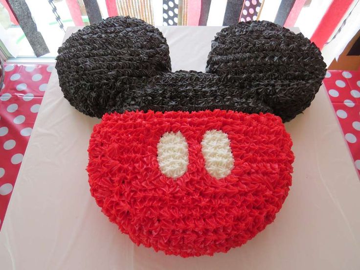 a mickey mouse cake with red and black frosting on it's face, sitting on a table