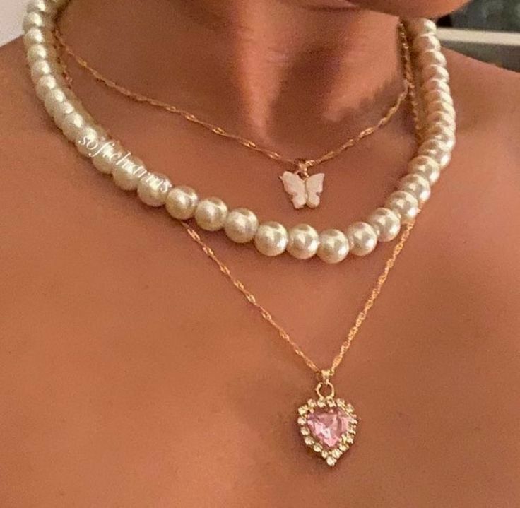 a woman wearing pearls and a necklace with a butterfly charm on it's neck