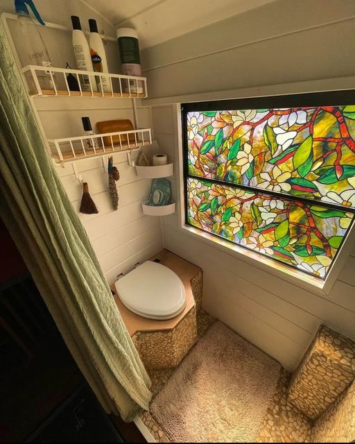 a small bathroom with a stained glass window above the toilet and shelves on the wall