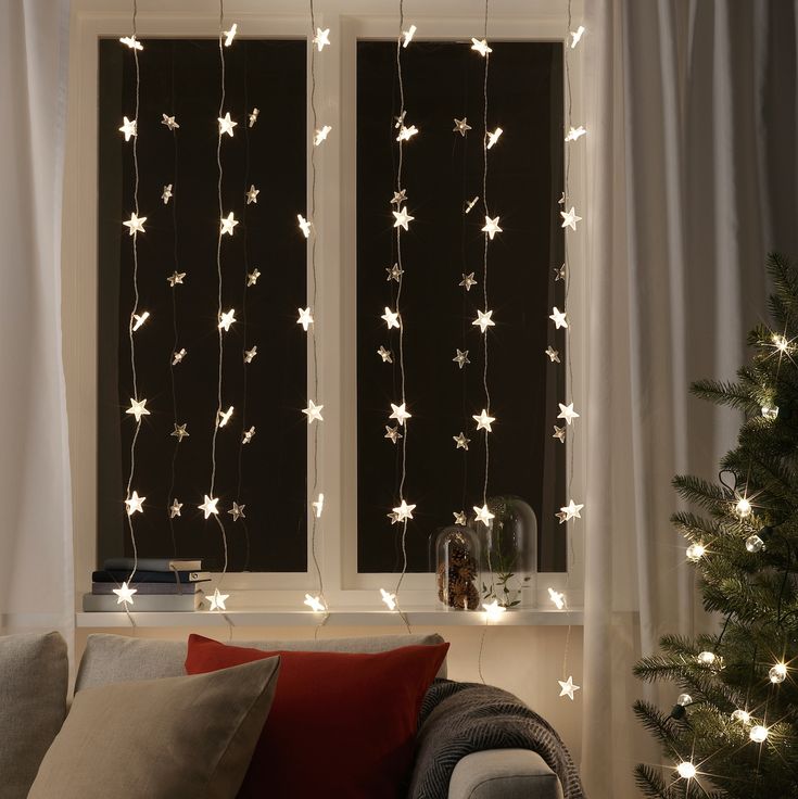 a living room filled with furniture and christmas lights hanging from the windows sill above them