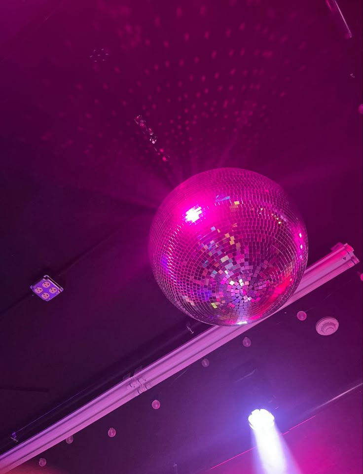 a disco ball hanging from the ceiling in front of a stage with lights on it