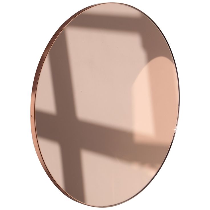 a round mirror reflecting the shadow of a cross on it's side, against a white background