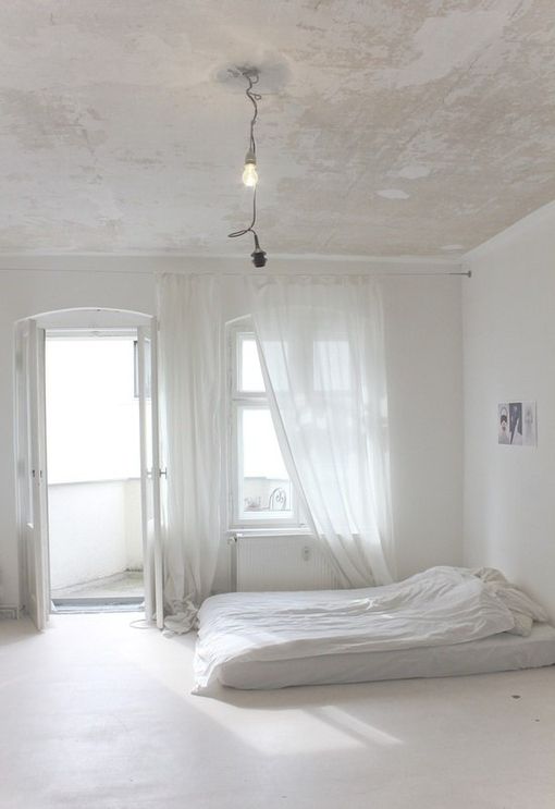 an empty bedroom with white walls and curtains