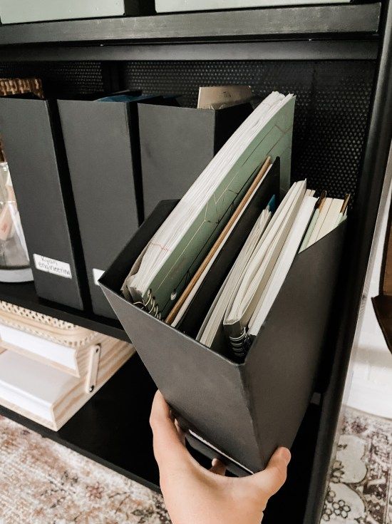 a person is holding a file cabinet full of files and folders in their hands