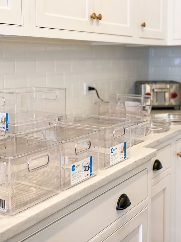 the kitchen counter has clear plastic containers on it