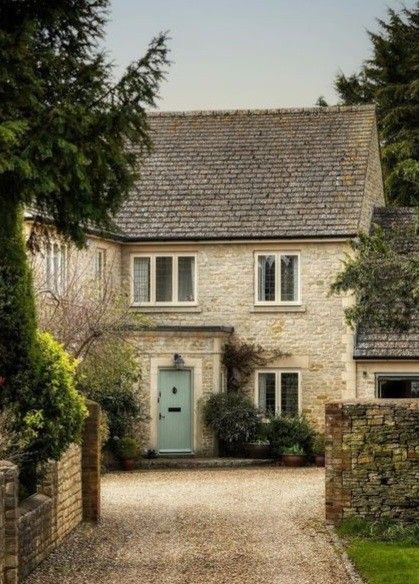 a stone house with a blue door surrounded by trees