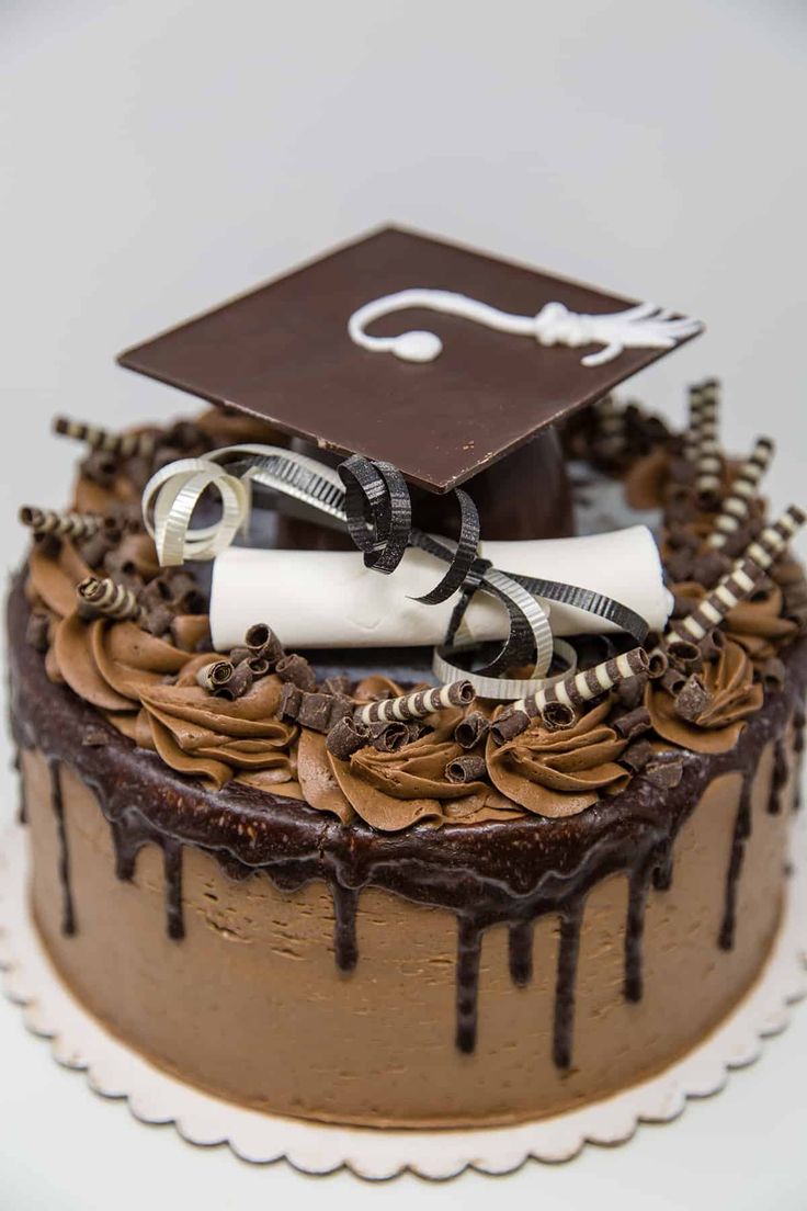 a graduation cake with chocolate icing and decorations on top is decorated with a mortar, diploma cap, and scroll