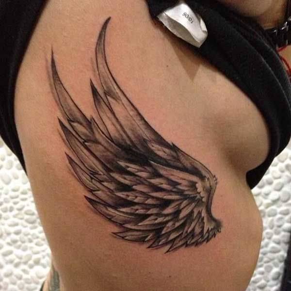 a woman's stomach with an angel wing tattoo on it