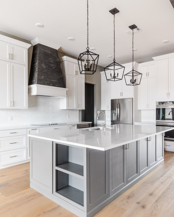 a kitchen with white cabinets and an island in the middle is lit by pendant lights