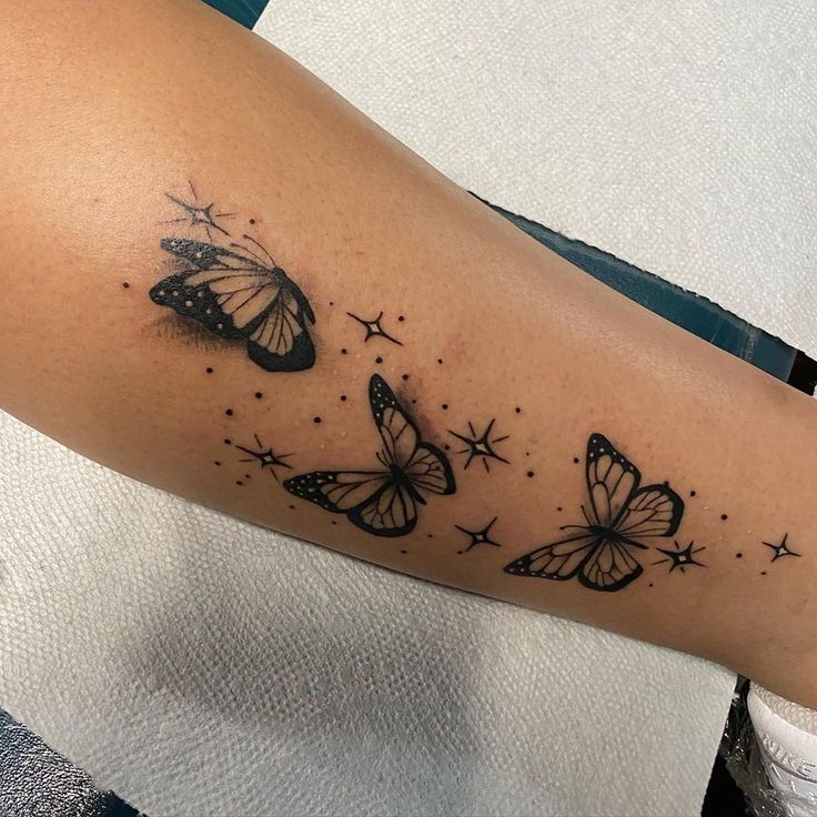 a woman's arm with butterflies and stars on the back of her left arm