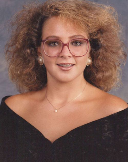 a woman with glasses is posing for a photo