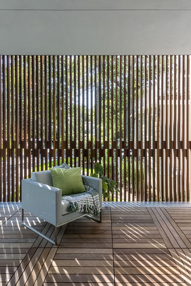 a white chair sitting on top of a wooden floor next to a wall covered in vertical slats