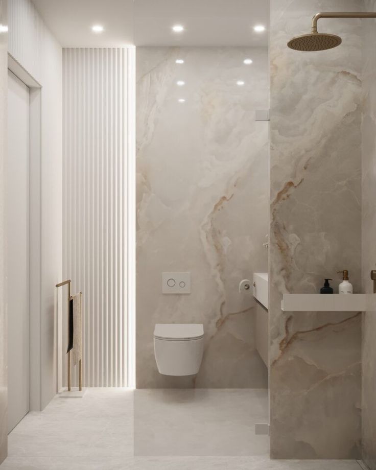 a bathroom with marble walls and flooring next to a white toilet in the corner