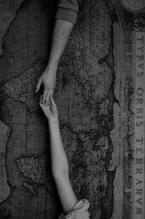 two people holding hands on top of a map