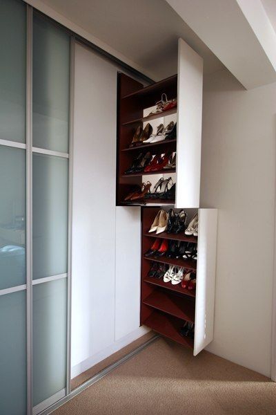 an empty closet with several pairs of shoes on the shelves and sliding glass doors leading to another room