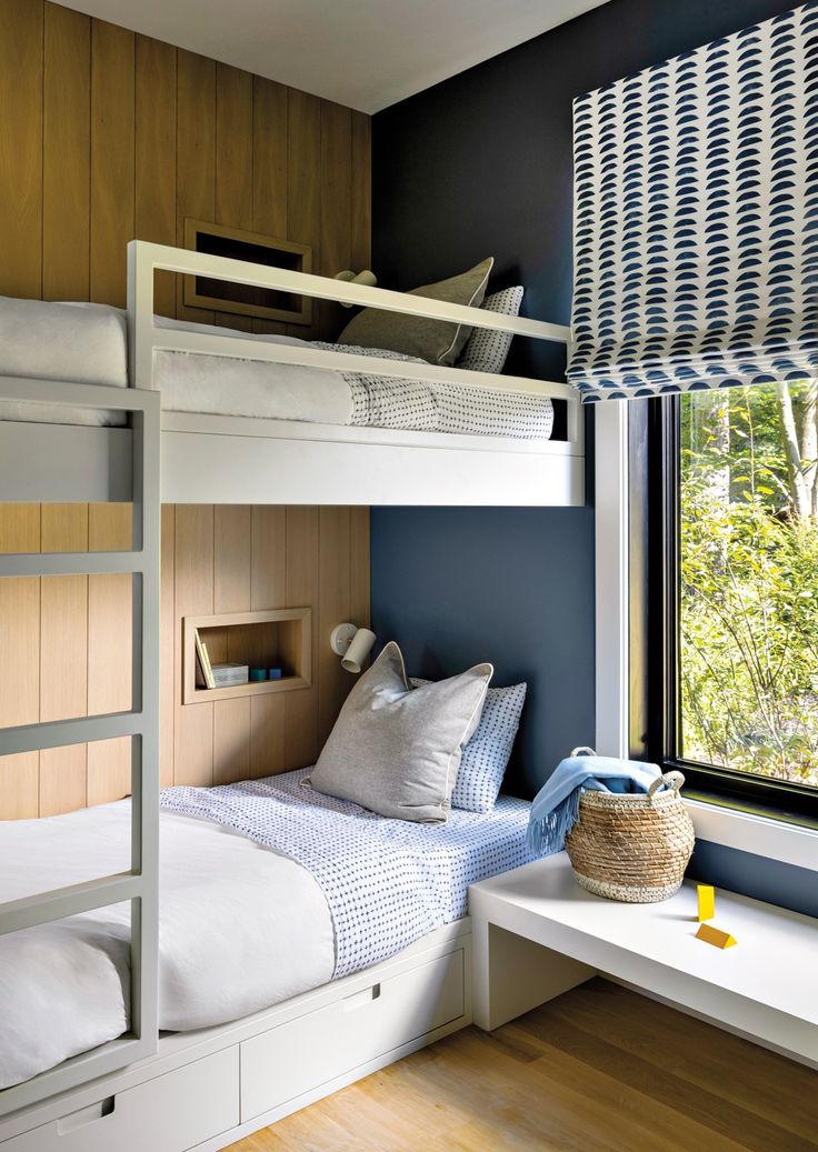 a bedroom with bunk beds and windows in the corner, along with a window seat