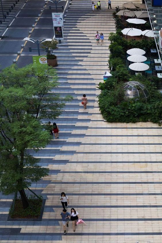 several people walking up and down the stairs at an outdoor shopping mall with umbrellas on them