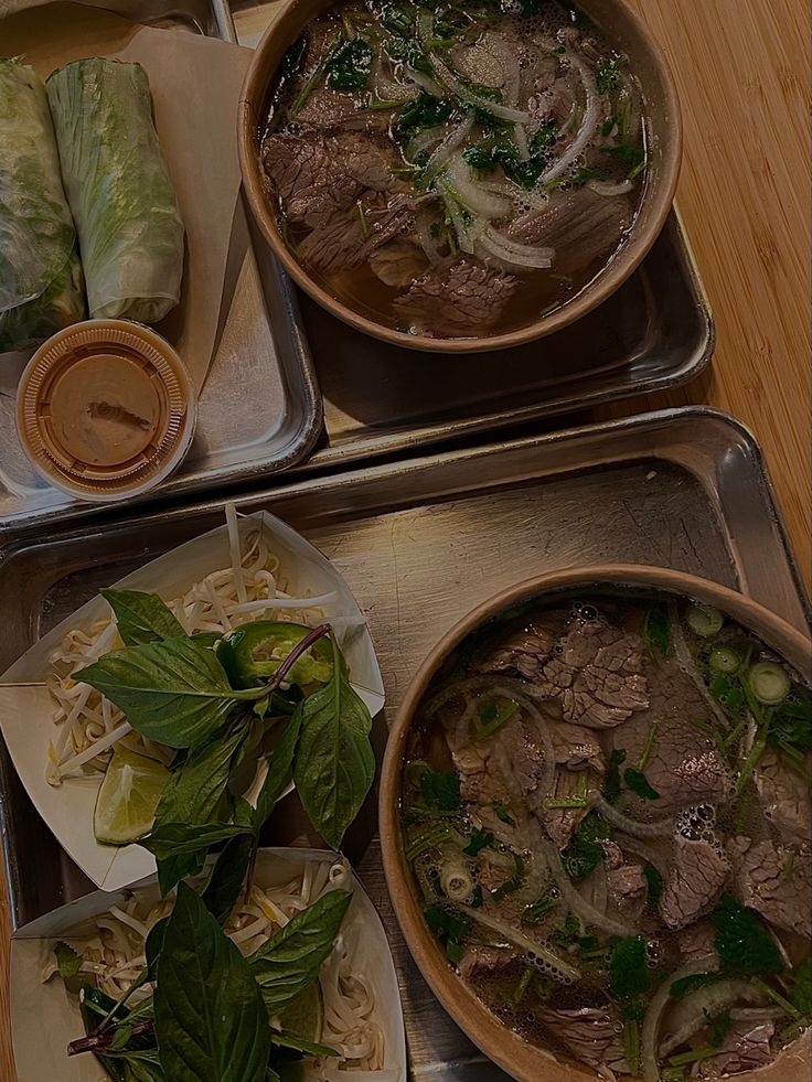 three trays filled with food on top of a wooden table next to each other