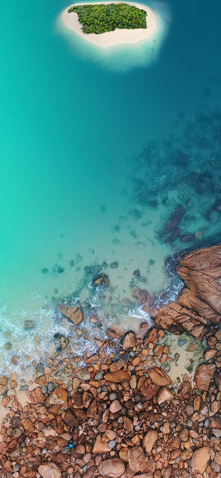 an aerial view of rocks and water in the ocean with a boat on it's side