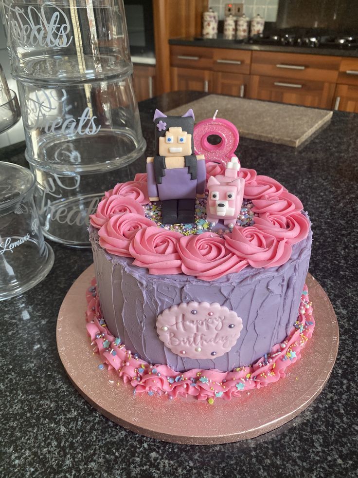 a cake with pink frosting on top of a table next to glasses and water bottles