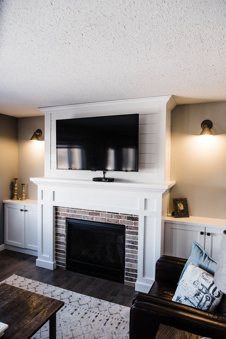 a living room with a fireplace and tv mounted on the wall above it's mantle